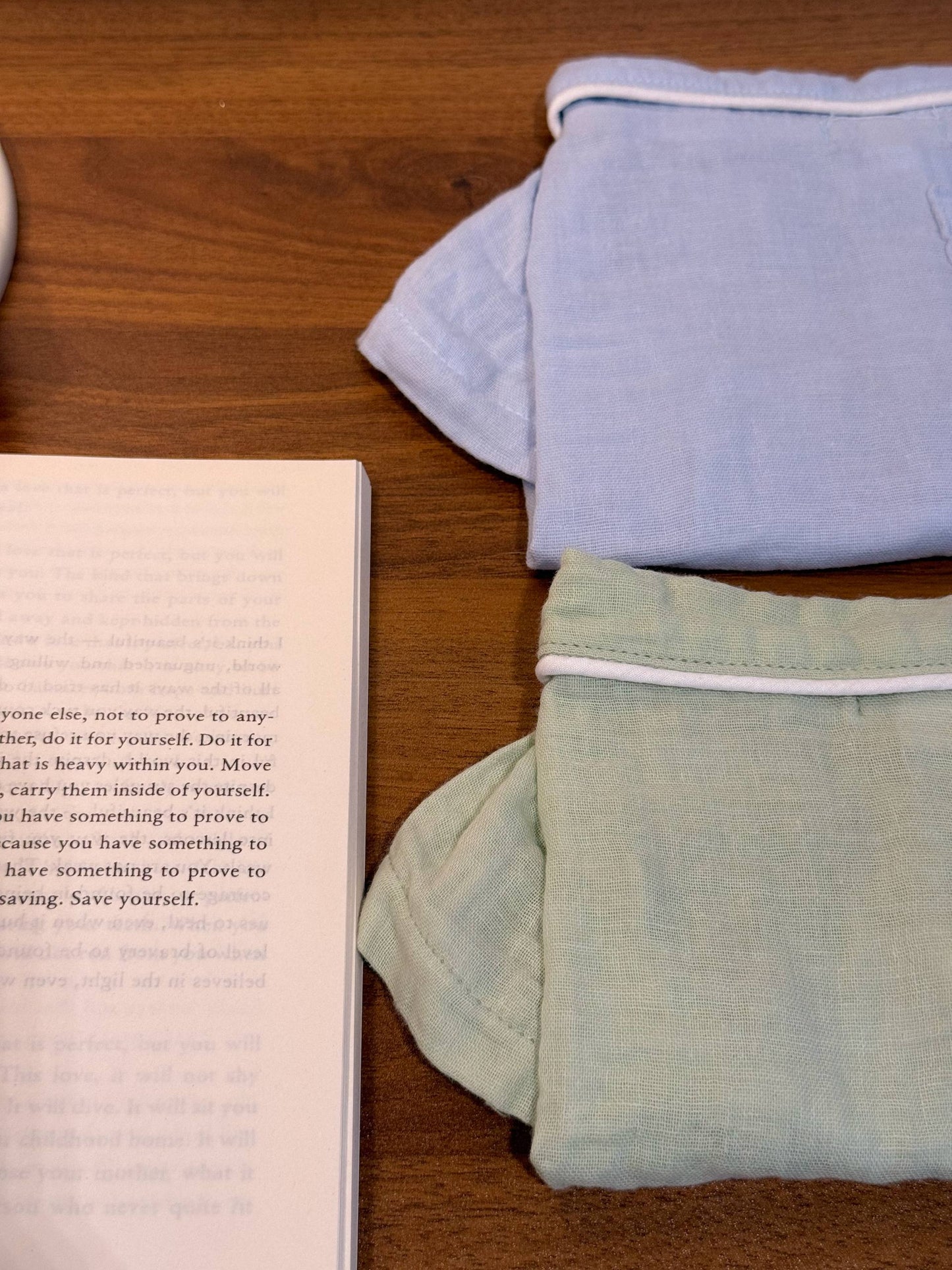 Two sets of folded pet pajamas in sage green and dusty blue 