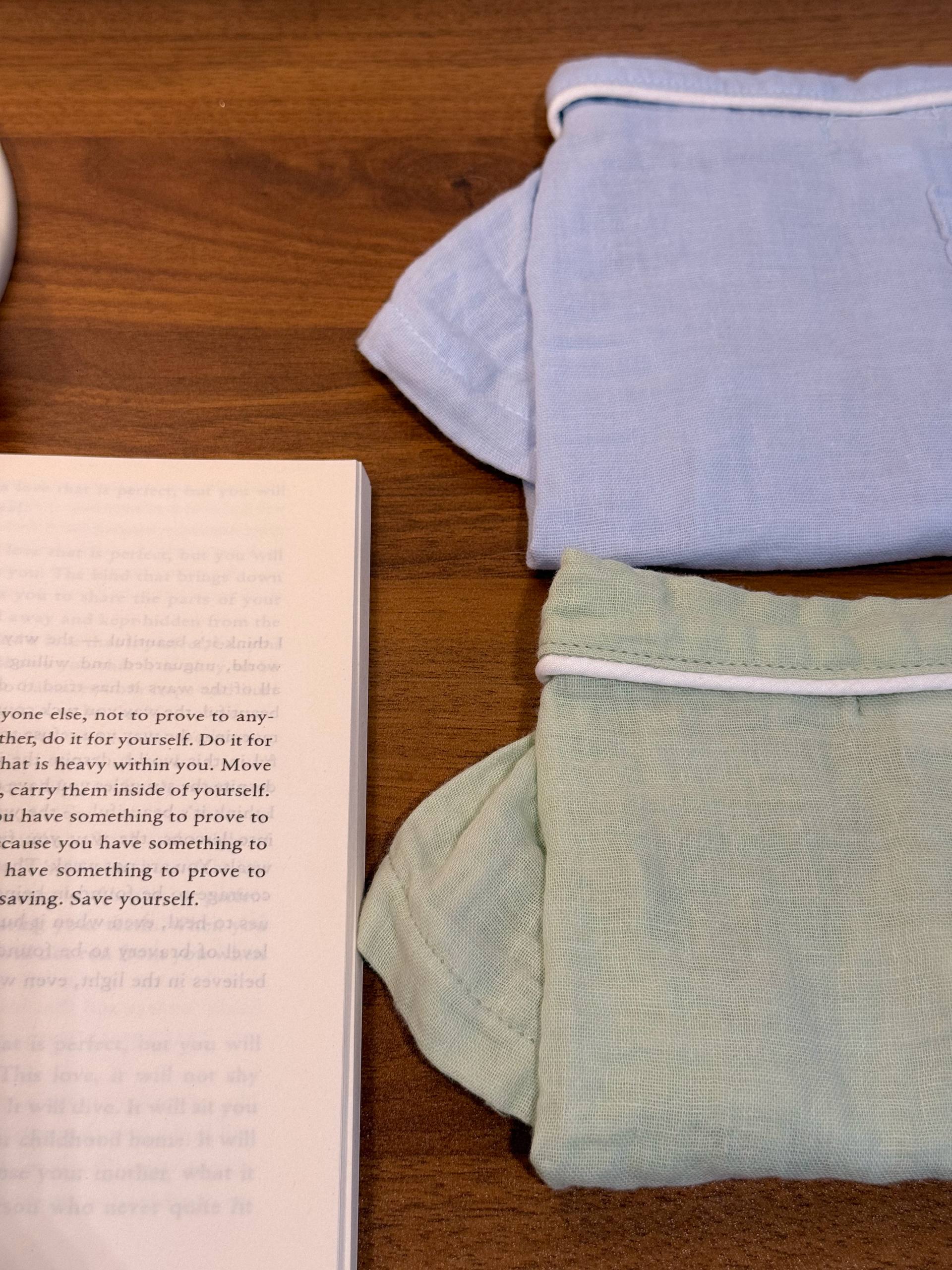 Two sets of folded pet pajamas in sage green and dusty blue 